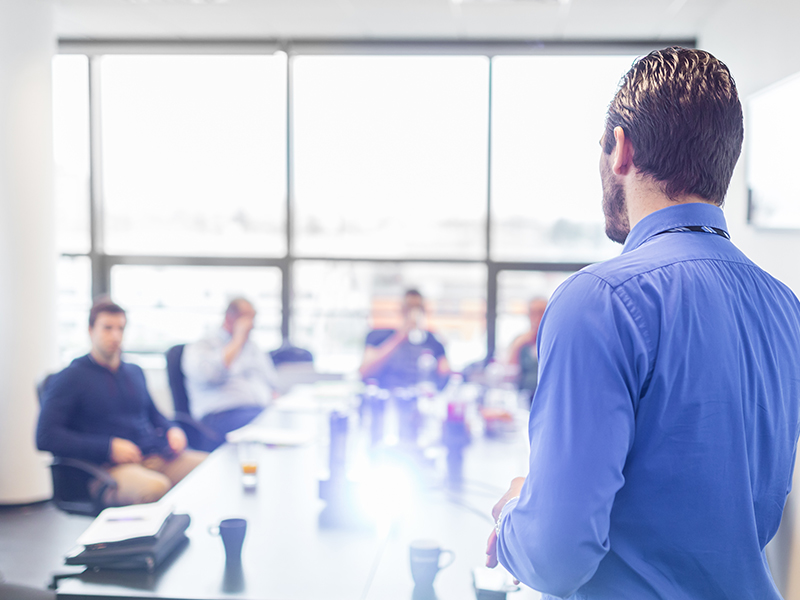 Business man making a presentation at office. Business executive delivering a presentation to his colleagues during meeting or in-house business training, explaining business plans to his employees.