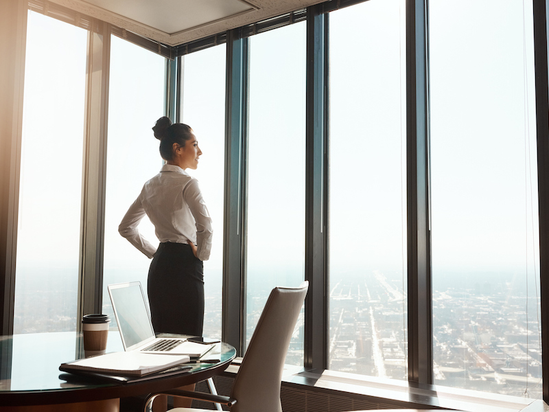 Rearview shot of an attractive young businesswoman standing with her hands on her hips in the office