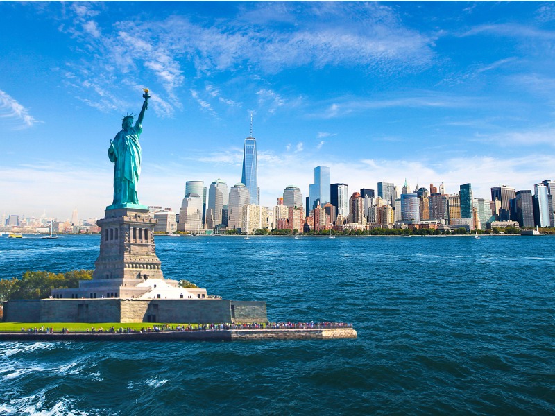 Statue of Liberty and New York City Skyline with Manhattan Financial District, World Trade Center, Empire State Building and Blue Sky