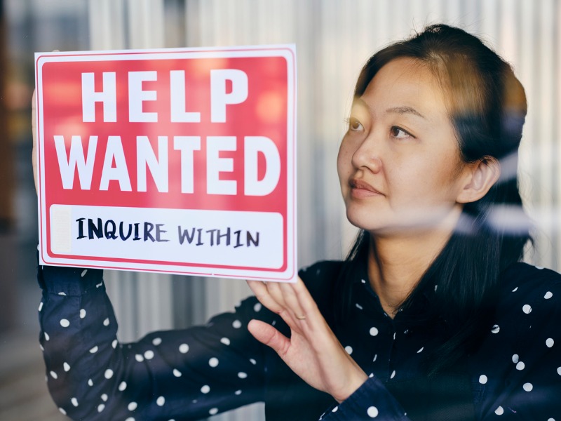 Business Owner Putting Up Help Wanted Sign stock photo