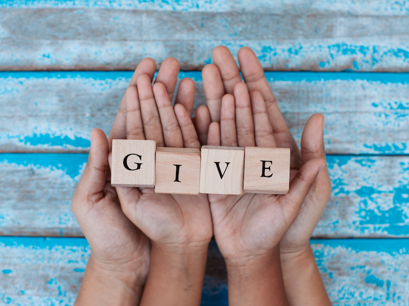 Alphabet letter wooden blocks with words GIVE in child and parents hands. Family and charity concept