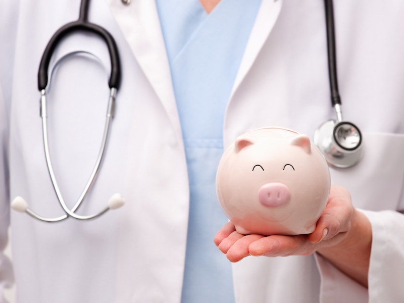 Female doctor with stethoscope holding piggy bank