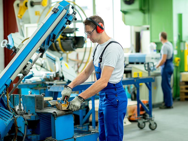 Worker in protective clothing in factory using machine