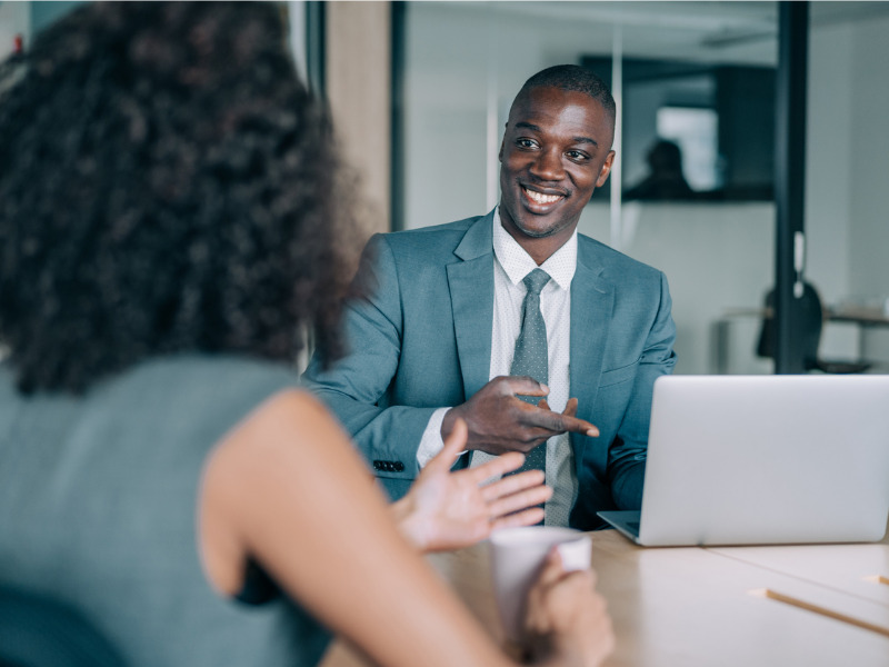 Two colleagues having a discussion around the boardroom table