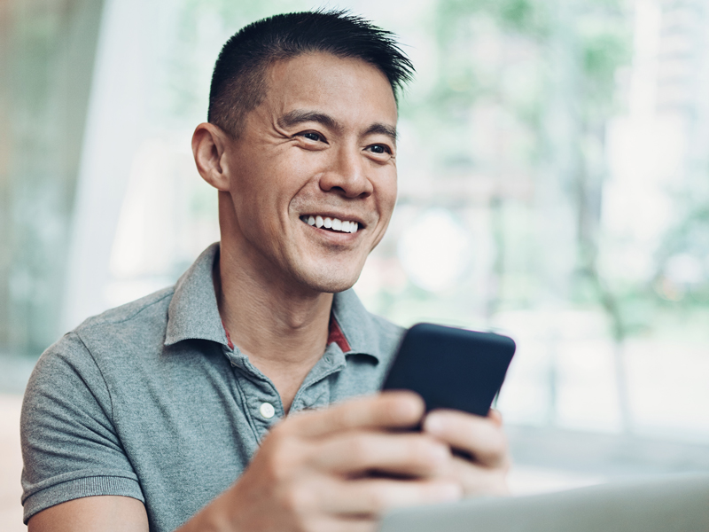 Man happily smiles at his phone.