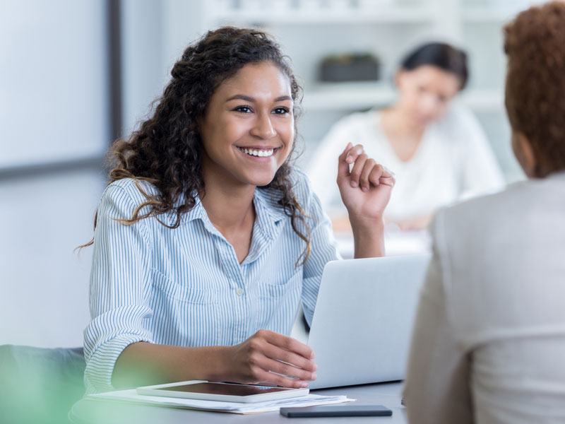 Businesswoman smiles while listening to colleague|