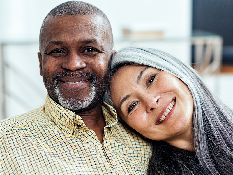 Happy senior couple sitting on the couch with women’s head resting on mans shoulder