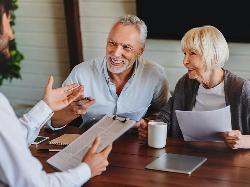 Happy aged couple consulting with insurance agent at home