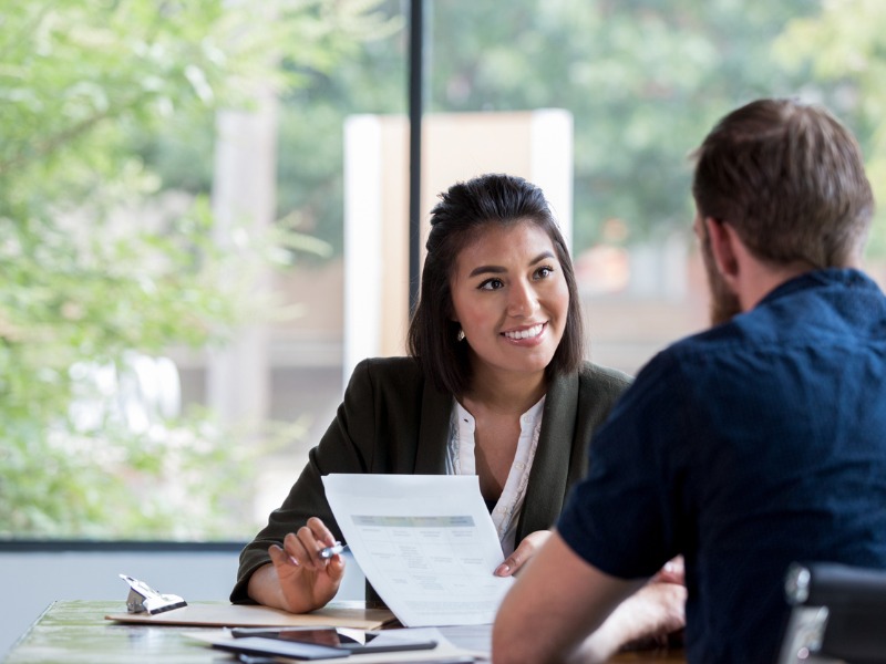 Businesswoman smiles while showing a document to a male associate