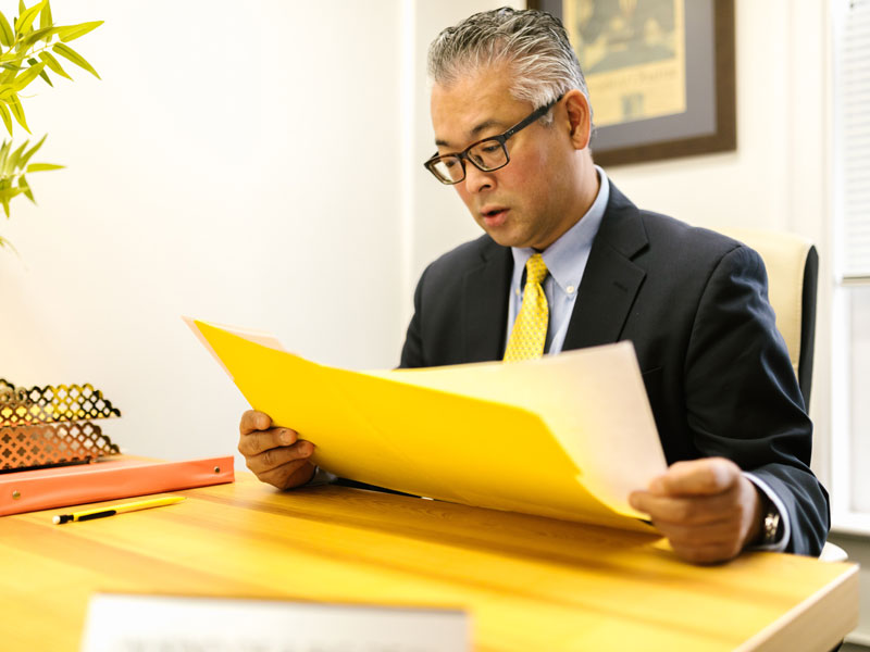 Man looking through a file around a desk|