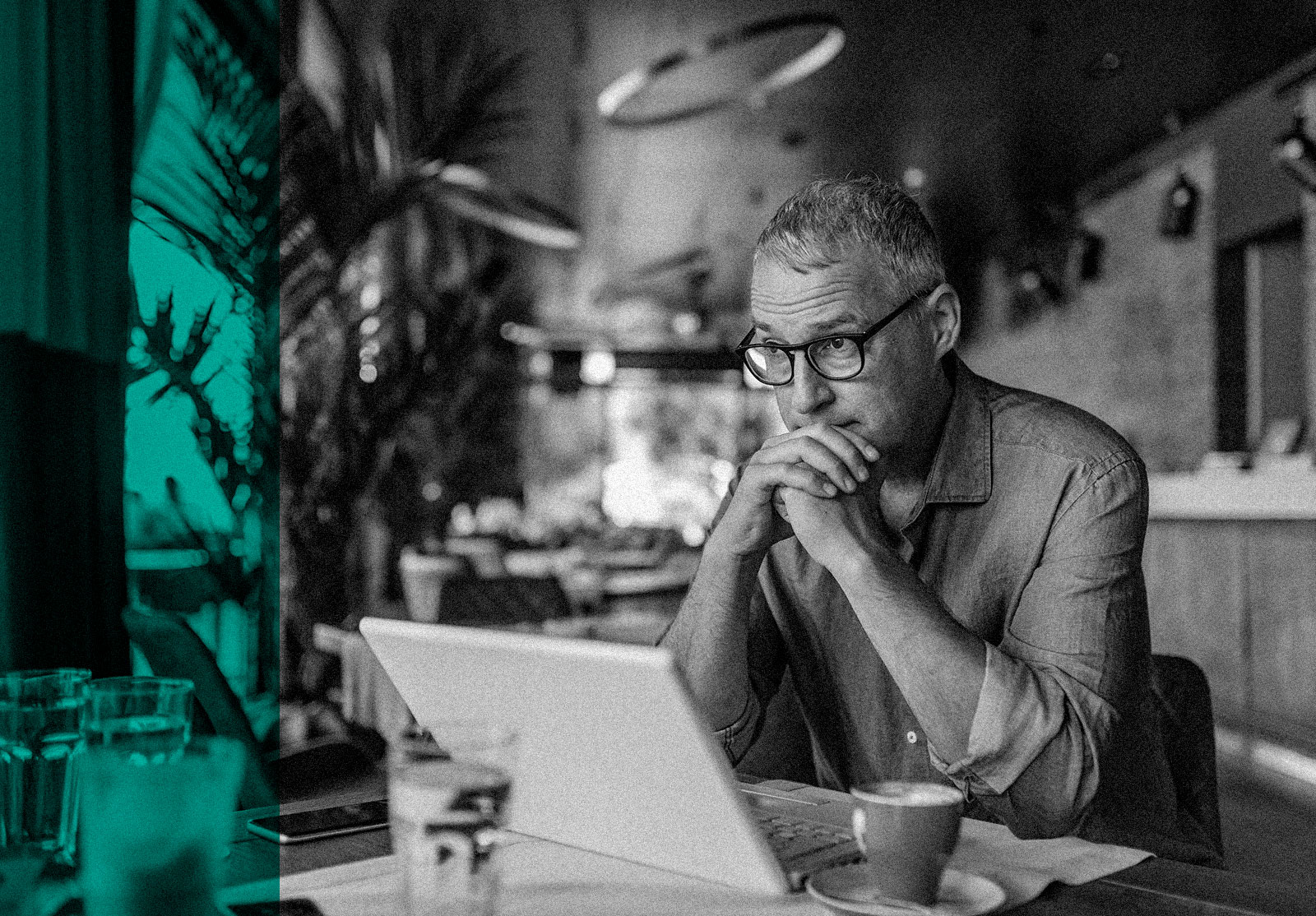 Worried man lookind at laptop in a café