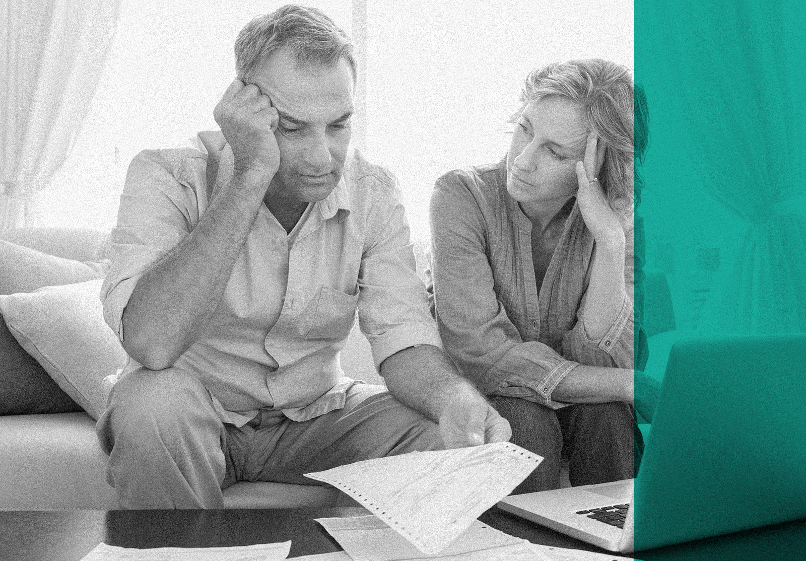 Worried couple using their laptop to pay their bills at home in the living room