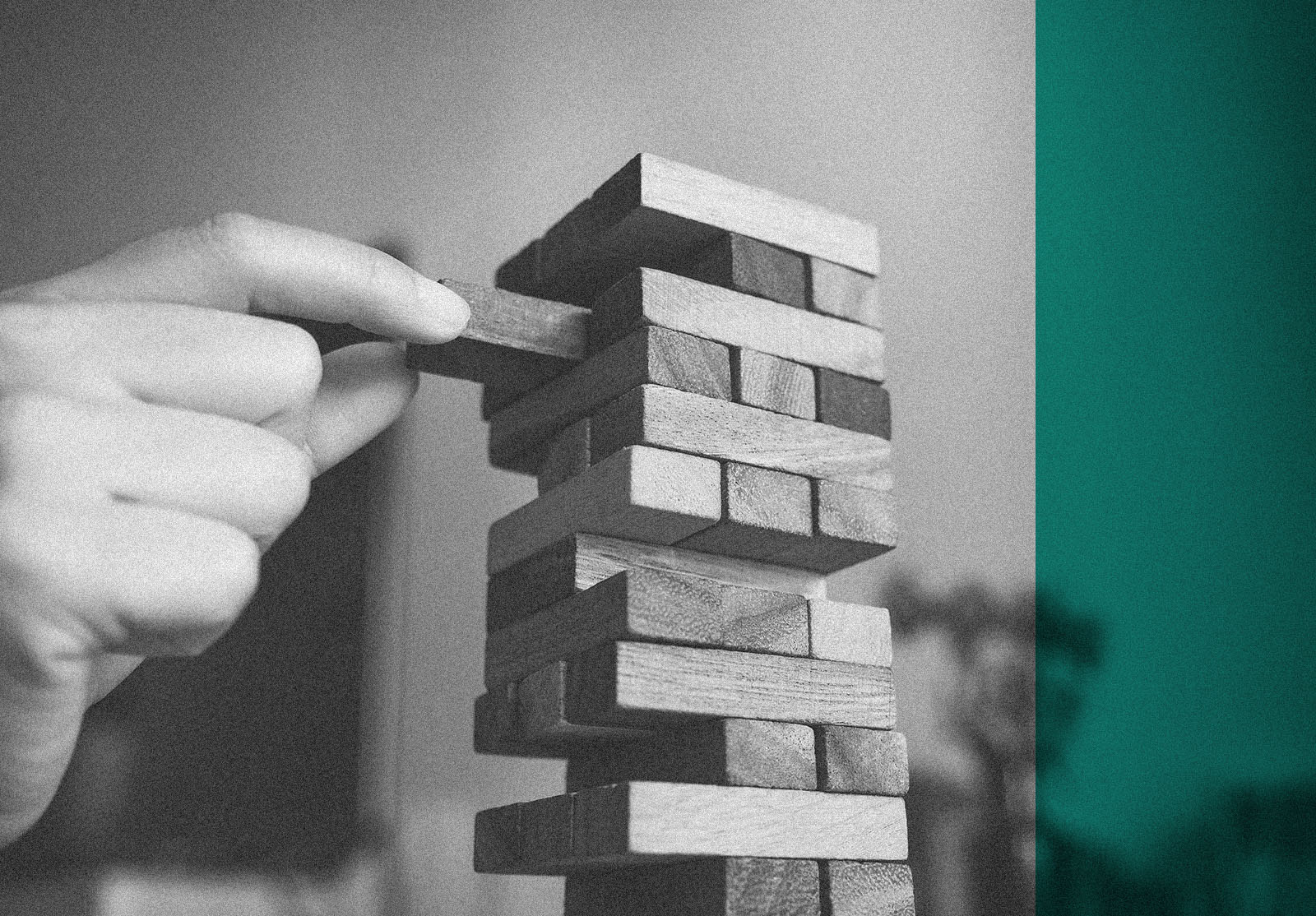 Closeup image of a hand holding and playing Jenga or Tumble tower wooden block game