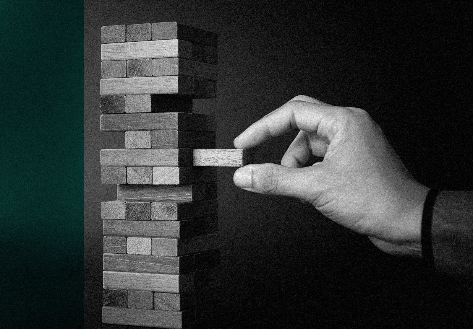 Planning, risk and strategy in business concept as businessman hand gambling pulling out a wooden block from a tower