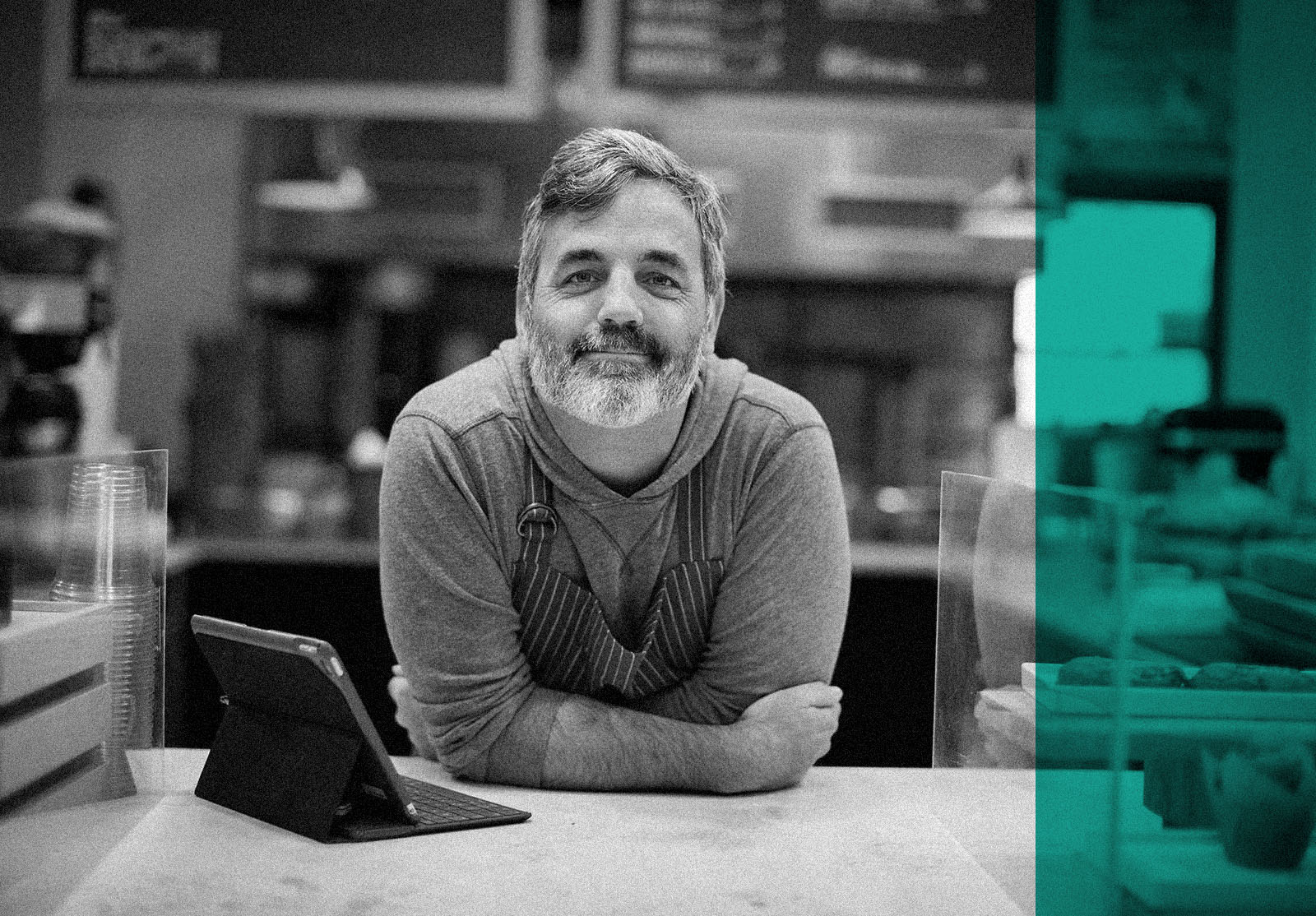 Portrait of smiling male owner with tablet computer on bar counter