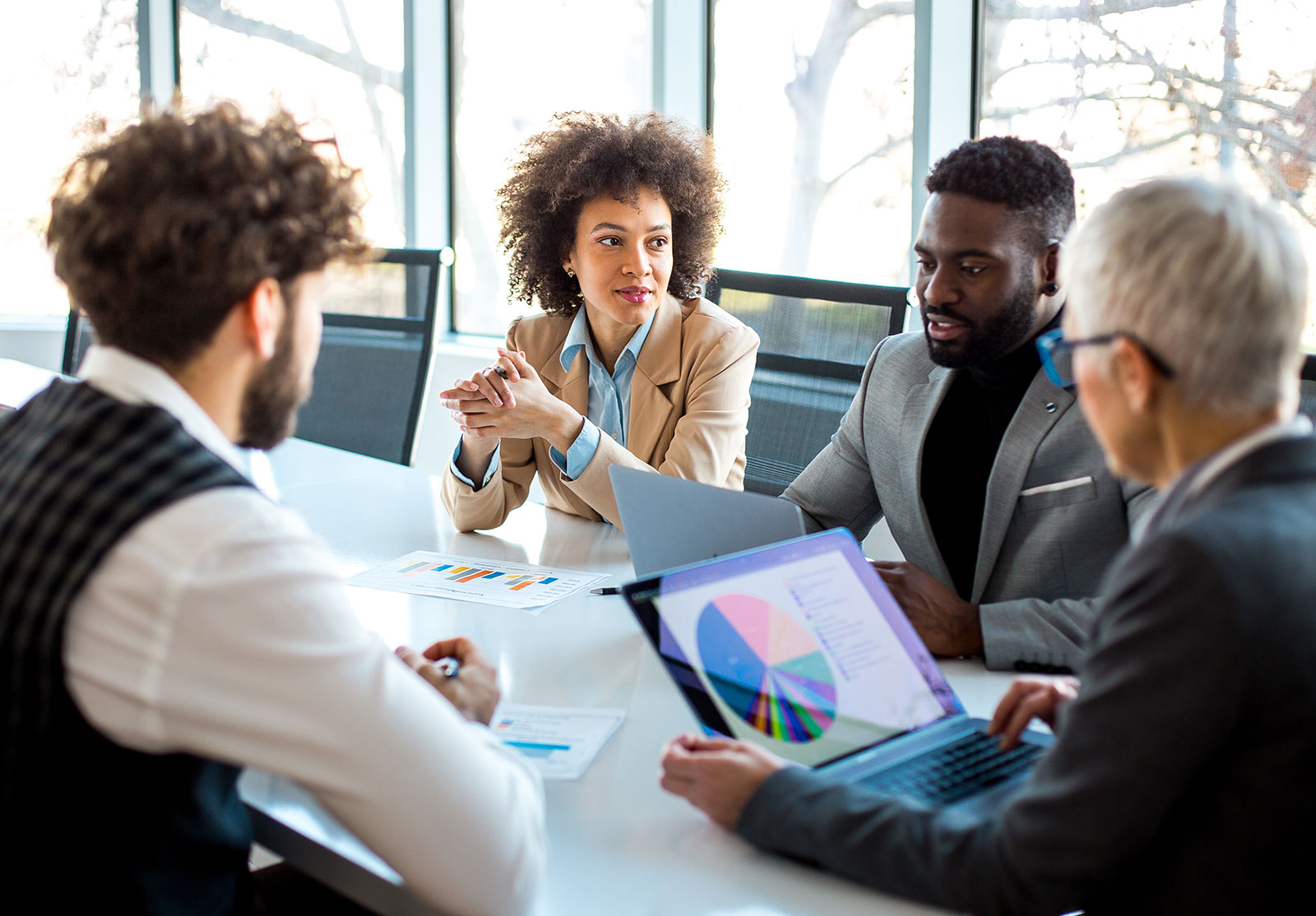 Discussion between group of advisors, looking at graphs, in boardroom