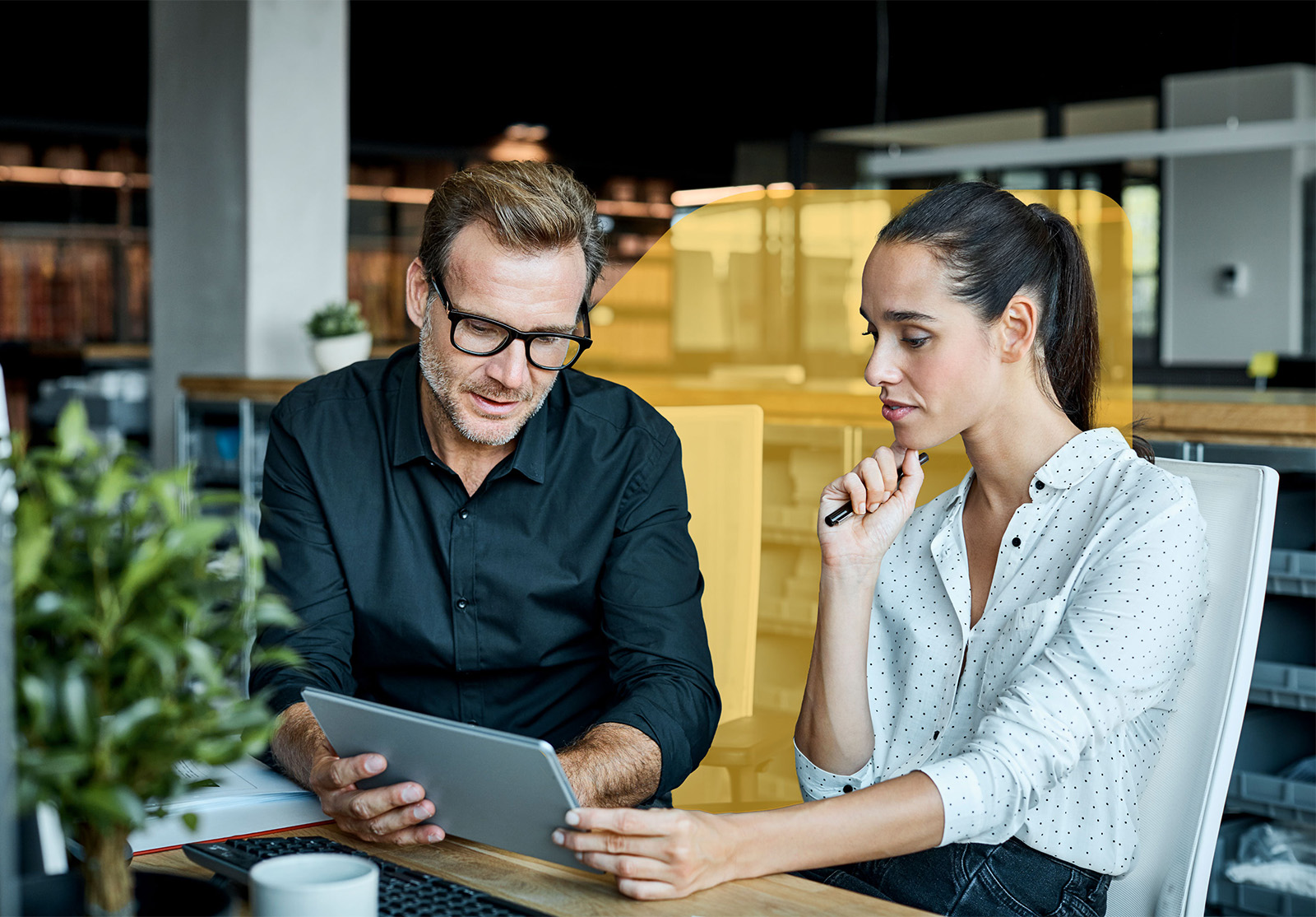 A man and a woman studying an iPad in professional setting