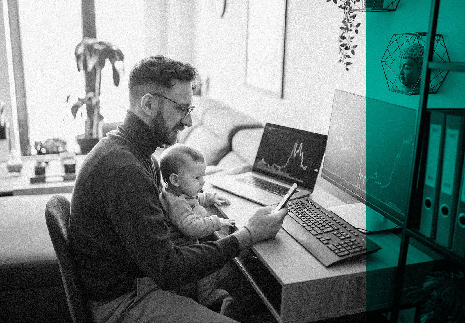 Man looking at financial data on computer while holding his baby